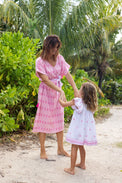 Mer St. Barth Capucine women's pink maxi caftan with rose embroidery, worn by a woman in a tropical garden setting.